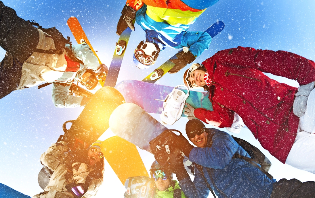 Gruppe glücklicher Snowboarder und Skifahrer im Kreis