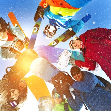 Gruppe glücklicher Snowboarder und Skifahrer im Kreis