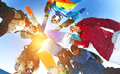 Gruppe glücklicher Snowboarder und Skifahrer im Kreis
